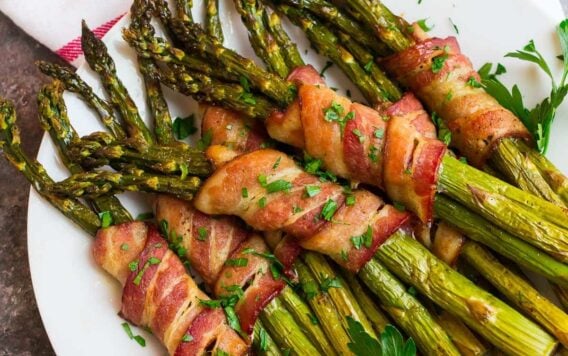 A white plate with bacon wrapped asparagus spears