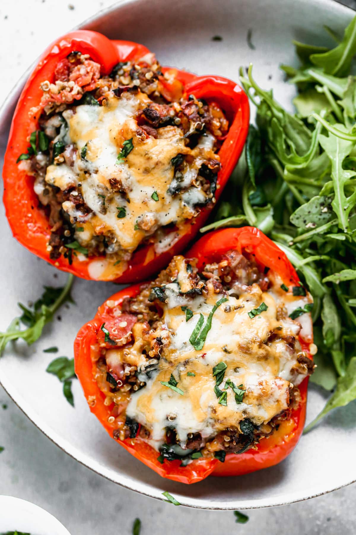 cheesy stuffed peppers in oven served on a plate with salad

