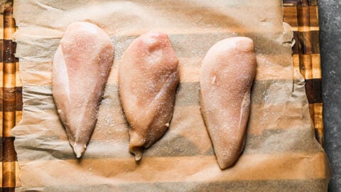 Three chicken breasts on a cutting board