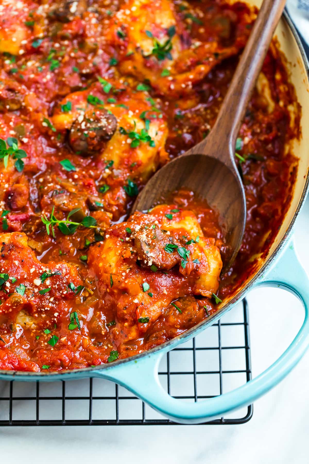 Healthy chicken cacciatore in a Dutch oven with a wooden spoon