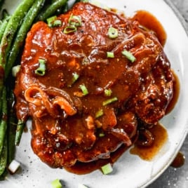 juicy crock pot pork chops on a plate with BBQ sauce