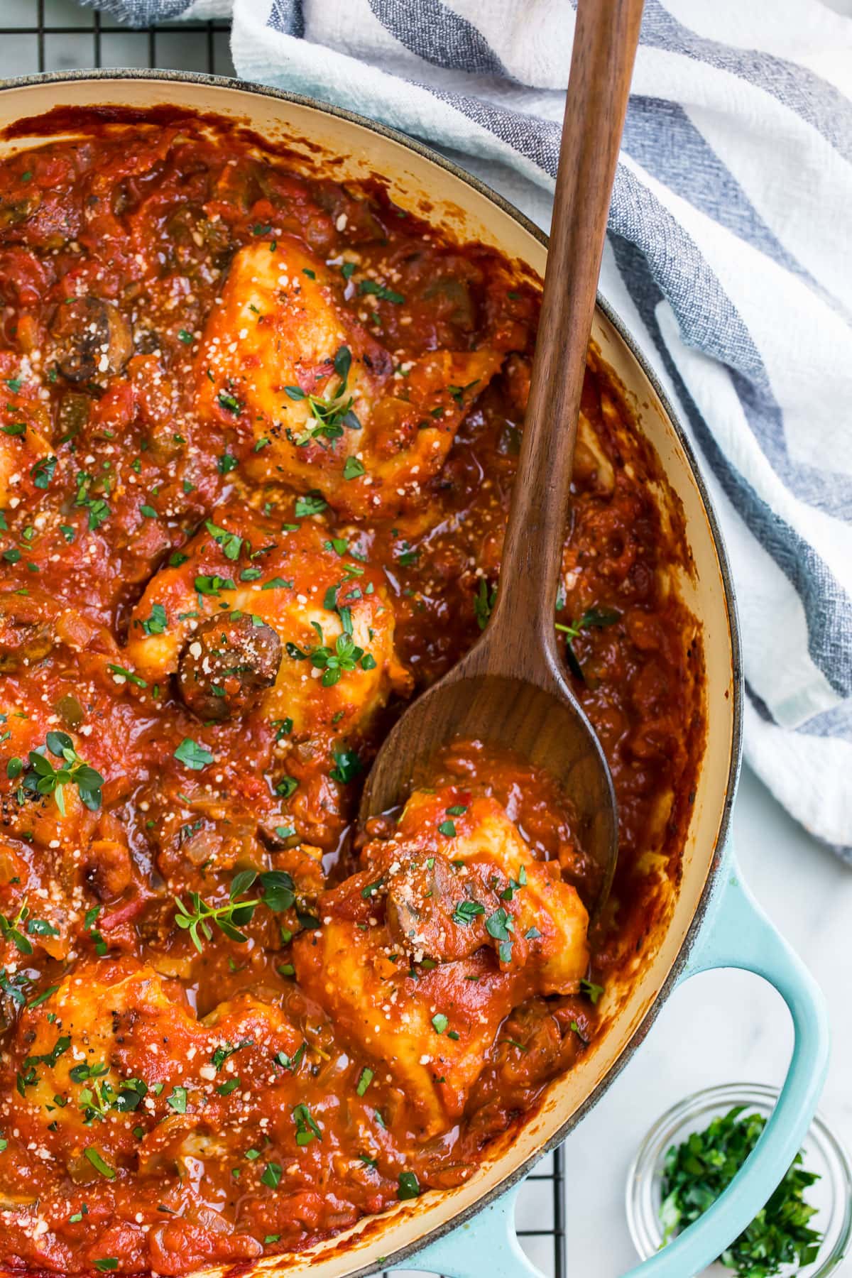 Stovetop Chicken cacciatore in a Dutch oven with a wooden spoon