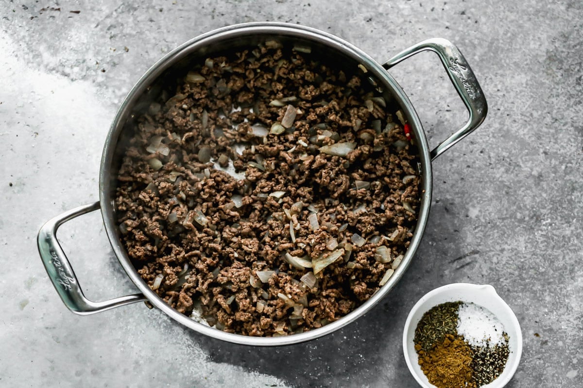 Ground beef in a skillet with sautéed onions and spices