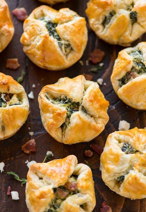 These Spinach Puffs are the ultimate easy, DELICIOUS appetizer! Buttery squares of puff pastry, filled with cream cheese, spinach, feta, and bacon, then baked to perfection. Easy to make ahead and everyone loves them!