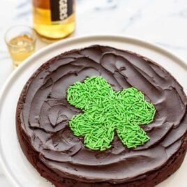 Chocolate, booze and sprinkles! A decadent, rich flourless chocolate cake with WHISKEY. Includes FREE PRINTABLE to make the cute sprinkle shamrock on top. A must make St. Patrick's Day dessert! Easy, gluten free, and so delicious. @wellplated
