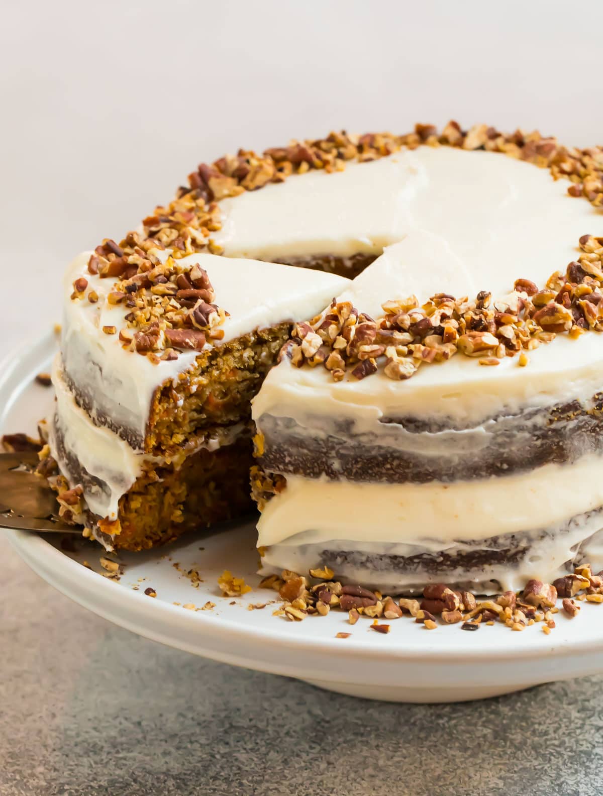 An almond flour gluten free carrot cake with cream cheese frosting and chopped nuts
