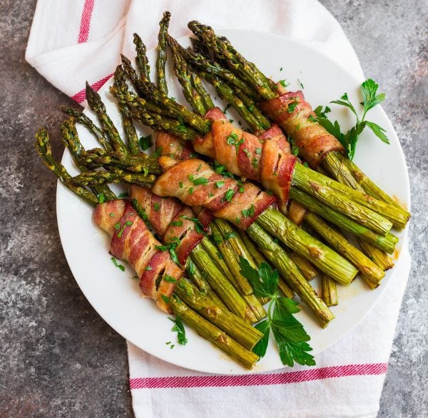 An overhead shot of delicious Bacon Wrapped Asparagus on a white plate