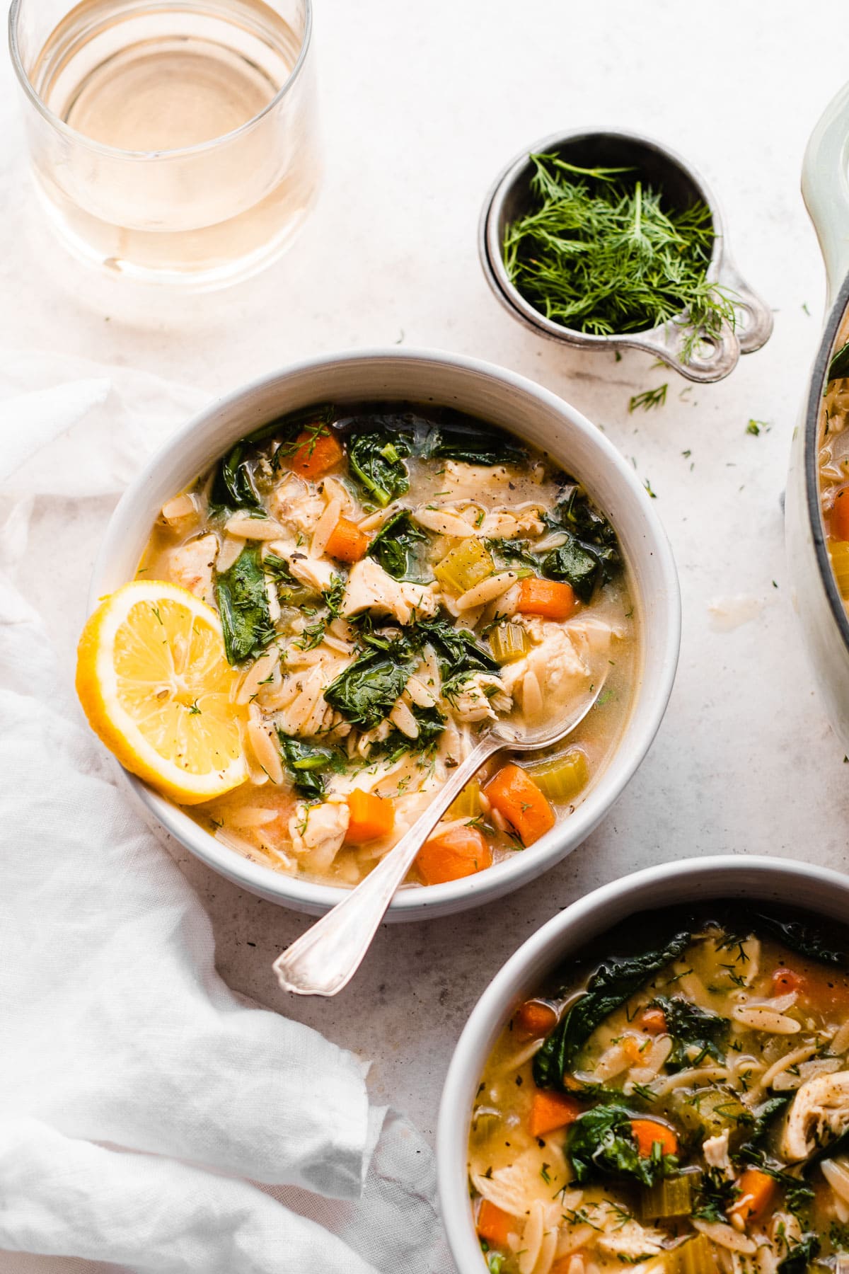 Two bowls of mediterranean lemon chicken orzo soup with spinach