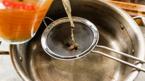 pouring broth through sieve