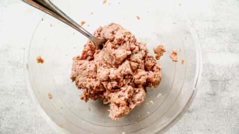 a glass bowl of uncooked ground turkey marinating in soy sauce