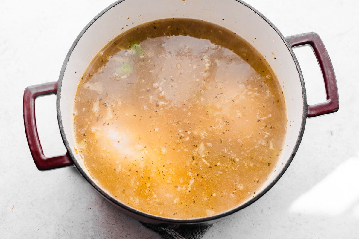 a steaming pot fo broth with chicken breasts