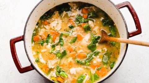 a steaming pot of lemon chicken orzo soup with spinach ready to serve
