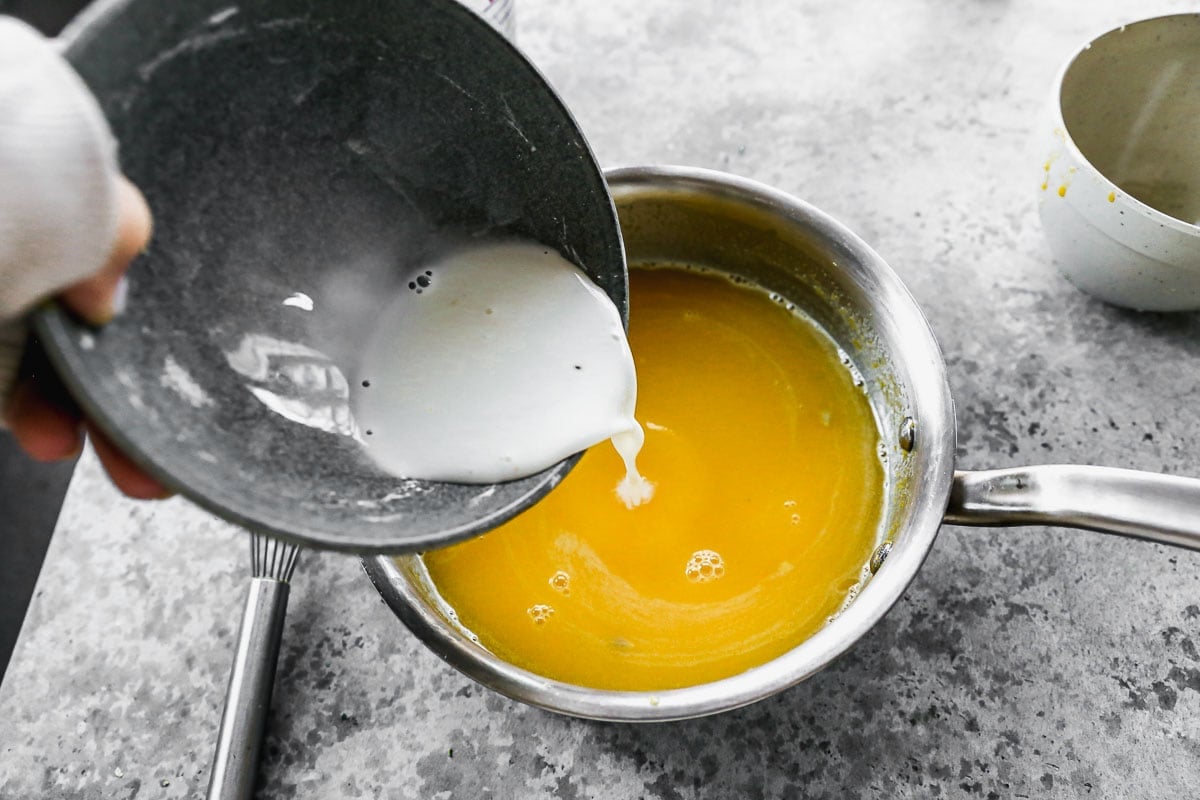 pouring cornstarch slurry into lemon tart saucepan
