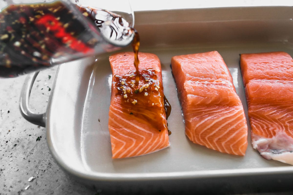 Pouring sauce onto salmon for salmon rice bowls