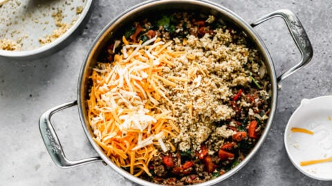 Cheese and quinoa being added to a skillet