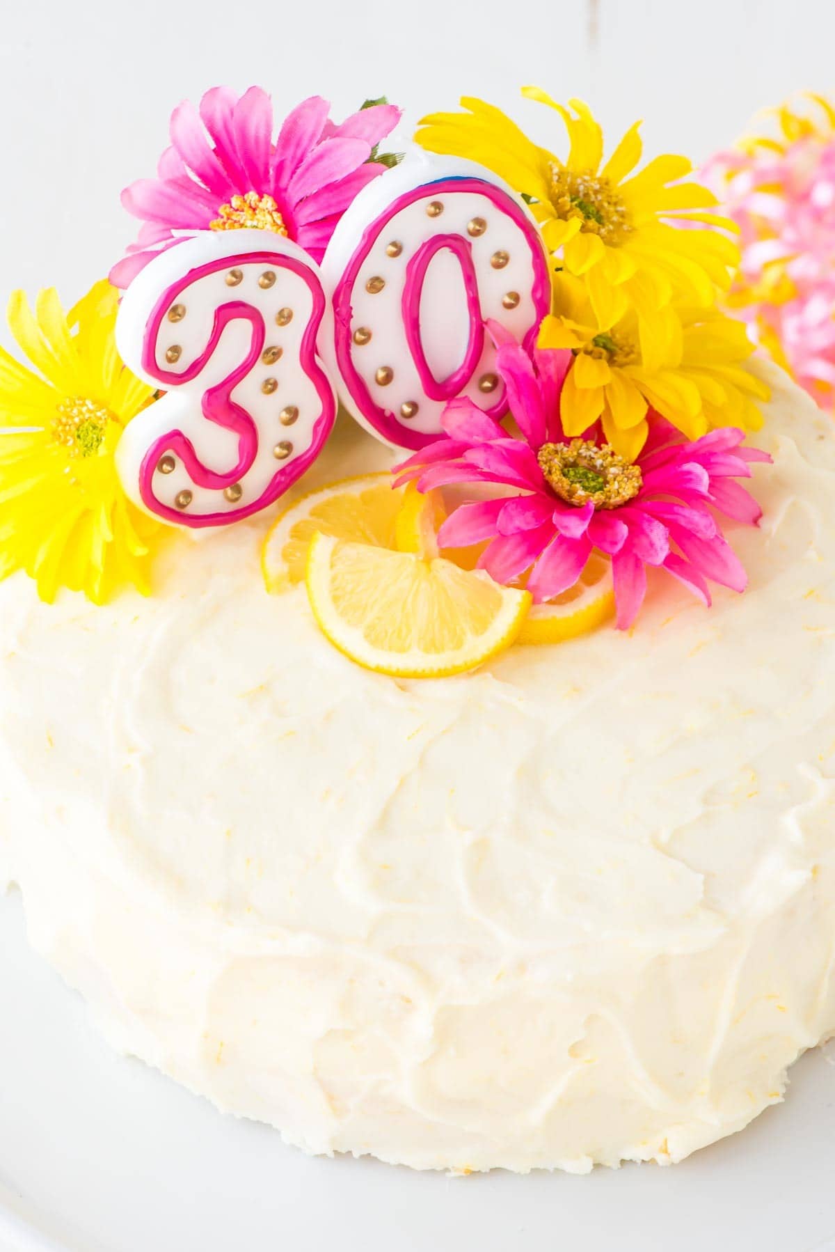 Healthy Lemon Cake topped with lemon cream cheese frosting, fresh spring flowers, and candles