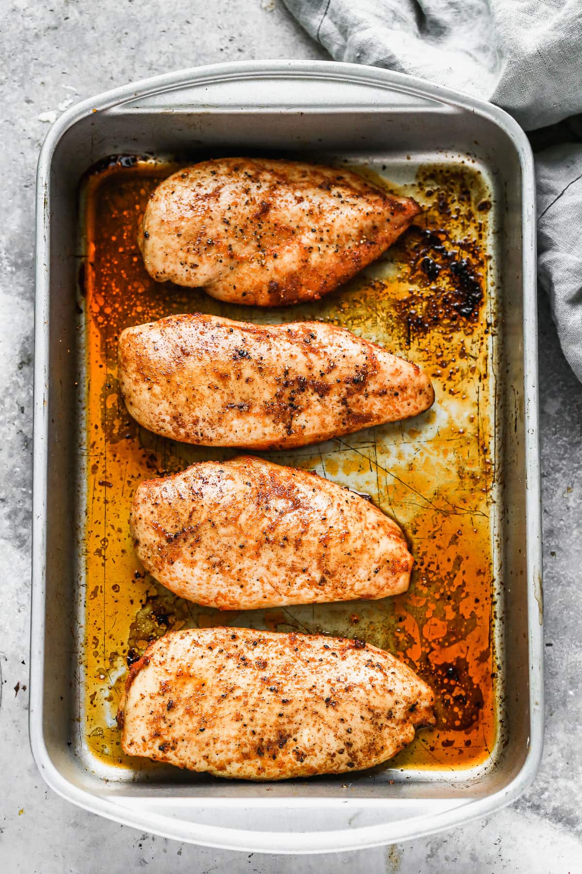 Four oven roasted chicken breasts in a pan