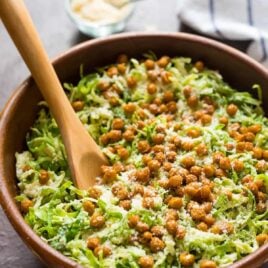 Caesar Shaved Brussel Sprout Salad with Roasted Chickpea Croutons. Perfect for healthy lunches or a holiday side dish. Made with shredded brussels sprouts, crispy roasted chickpeas, and creamy Caesar dressing. Easy and low carb!