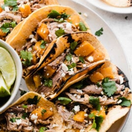 Slow Cooker Pulled Pork Tacos with butternut squash served in corn tortillas with cilantro, like and queso fresco