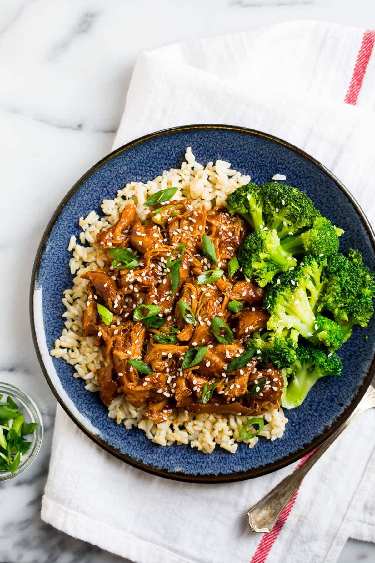 Healthy slow cooker honey garlic boneless skinless chicken thighs served on a plate with rice and broccoli