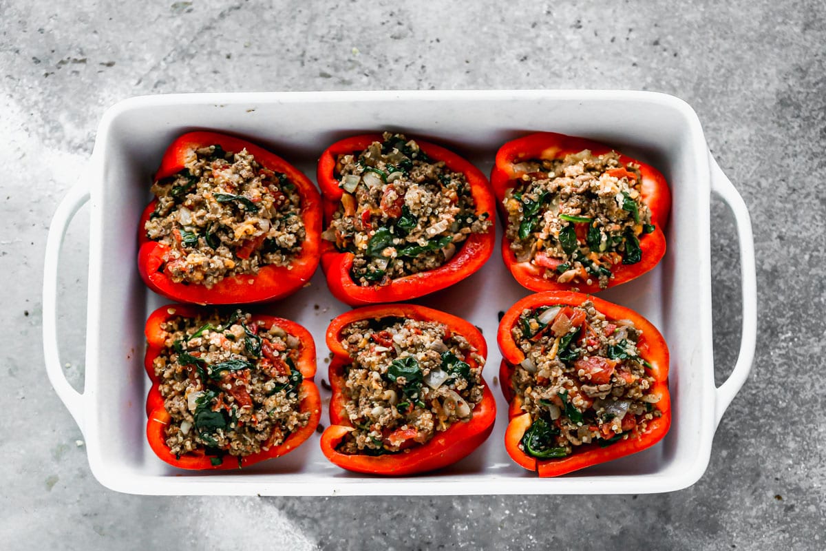 Uncooked classic stuffed peppers with quinoa in a baking dish