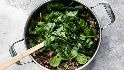 Spinach being added to a skillet