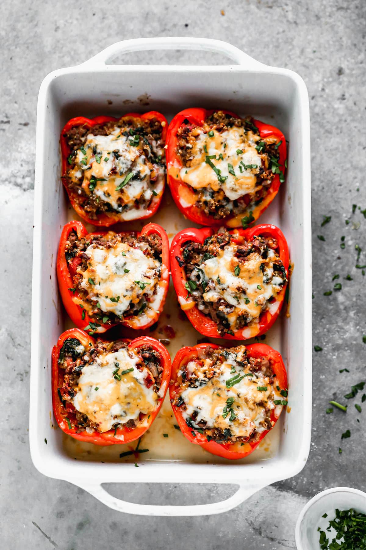 stuffed peppers with ground beef in a baking dish with quinoa, cheese, and Italian herbs
